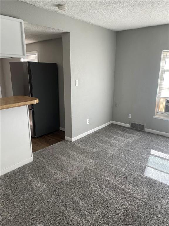 carpeted empty room with a textured ceiling