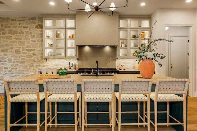 kitchen with tasteful backsplash, hardwood / wood-style floors, a center island with sink, and a breakfast bar