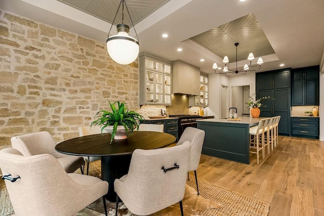 dining space featuring light wood-type flooring, a chandelier, and a raised ceiling