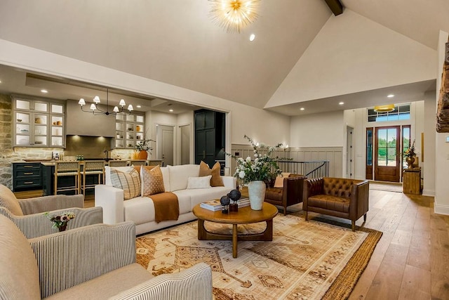 living room featuring high vaulted ceiling, light hardwood / wood-style floors, beam ceiling, and a notable chandelier