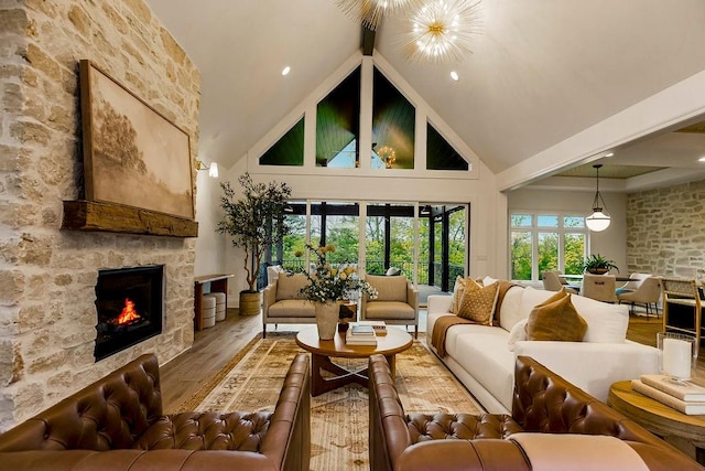 living room with high vaulted ceiling, hardwood / wood-style flooring, beamed ceiling, and a stone fireplace