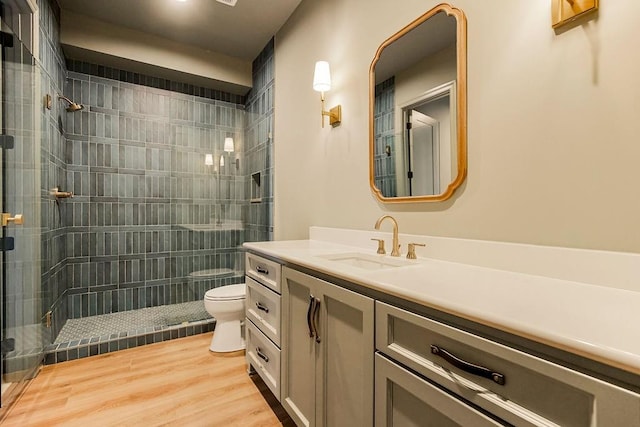 bathroom featuring wood-type flooring, toilet, walk in shower, and vanity