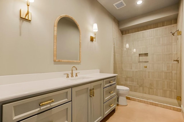 bathroom with vanity, toilet, tiled shower, and tile patterned floors