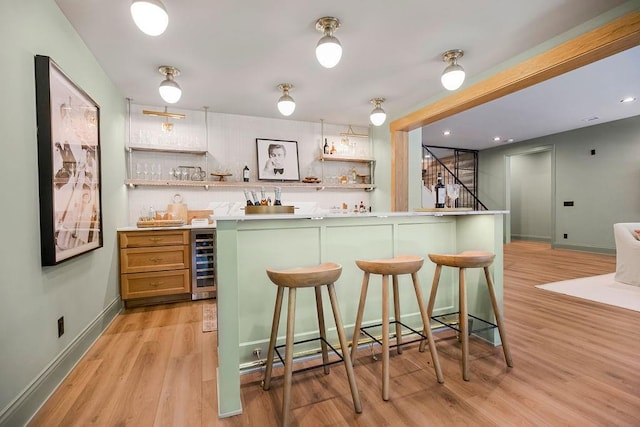 kitchen with light wood-type flooring, white cabinets, a kitchen bar, and beverage cooler