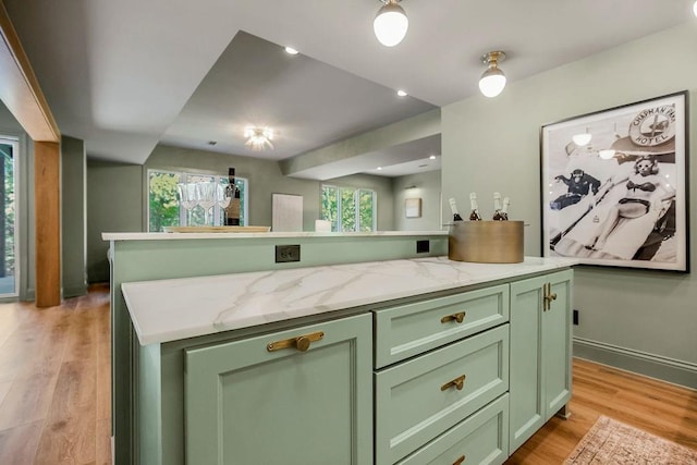 kitchen featuring light hardwood / wood-style flooring, green cabinetry, and light stone countertops