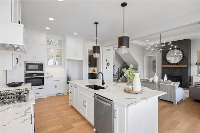 kitchen with light hardwood / wood-style floors, stainless steel appliances, decorative light fixtures, sink, and an inviting chandelier