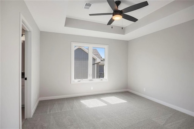 unfurnished room with ceiling fan, carpet flooring, and a tray ceiling