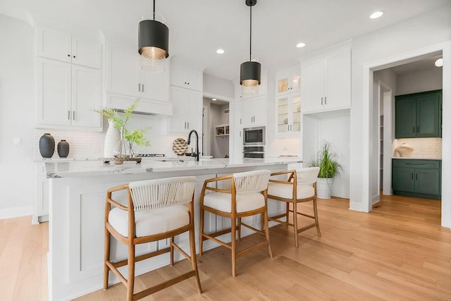 8009 Millridge St, Shawnee, KS 66220 - kitchen with appliances with stainless steel finishes, white cabinetry, backsplash, a kitchen island with sink, and light countertops