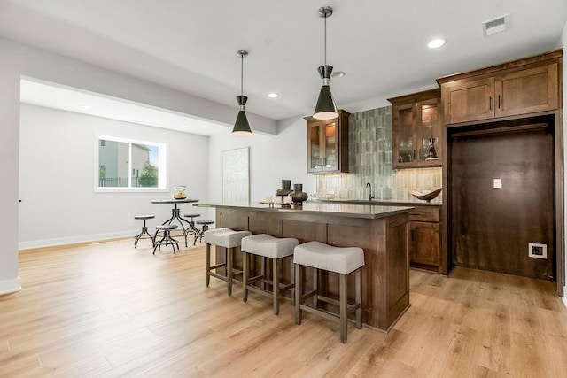 8009 Millridge St, Shawnee, KS 66220 - bar featuring light wood-style floors, tasteful backsplash, recessed lighting, and hanging light fixtures