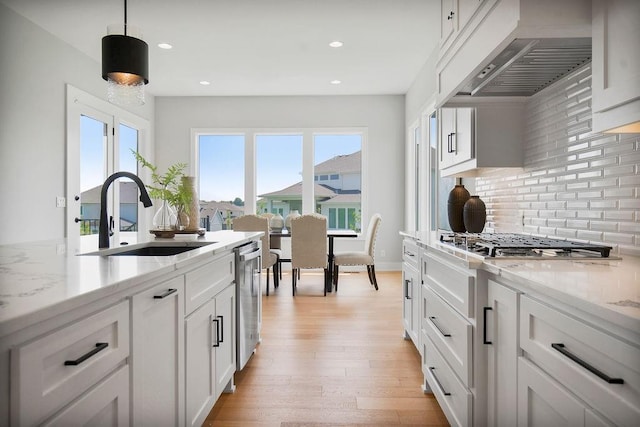 8009 Millridge St, Shawnee, KS 66220 - kitchen with custom exhaust hood, stainless steel appliances, backsplash, white cabinets, and light wood-style floors