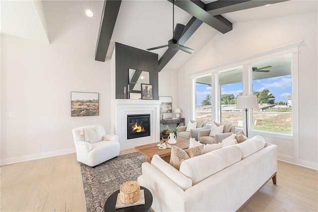 living room featuring a fireplace, light wood-type flooring, lofted ceiling with beams, and ceiling fan