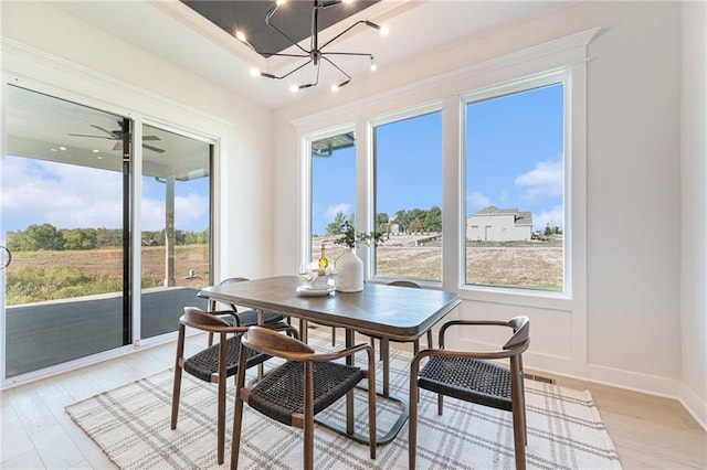 dining room featuring ceiling fan with notable chandelier and light hardwood / wood-style flooring