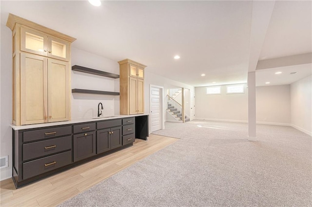 bar with dark brown cabinetry, sink, light wood-type flooring, and cream cabinetry