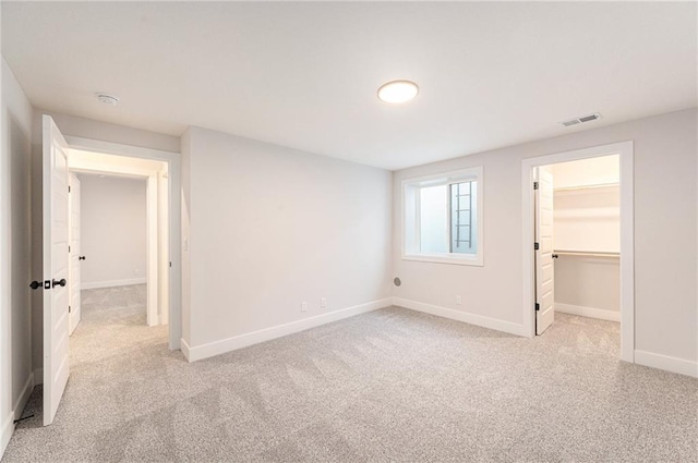 unfurnished bedroom with light colored carpet, a spacious closet, and a closet