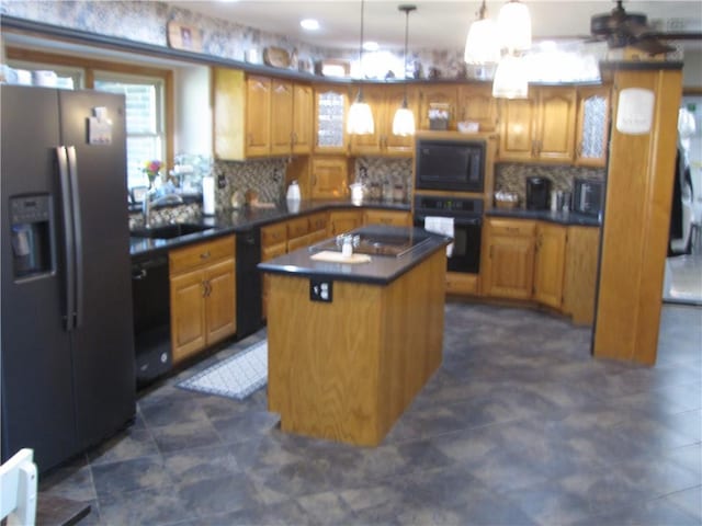 kitchen with an island with sink, black appliances, backsplash, dark tile flooring, and sink