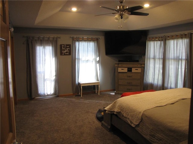 carpeted bedroom featuring ceiling fan and a raised ceiling