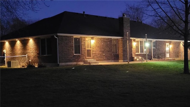 back house at night featuring a yard