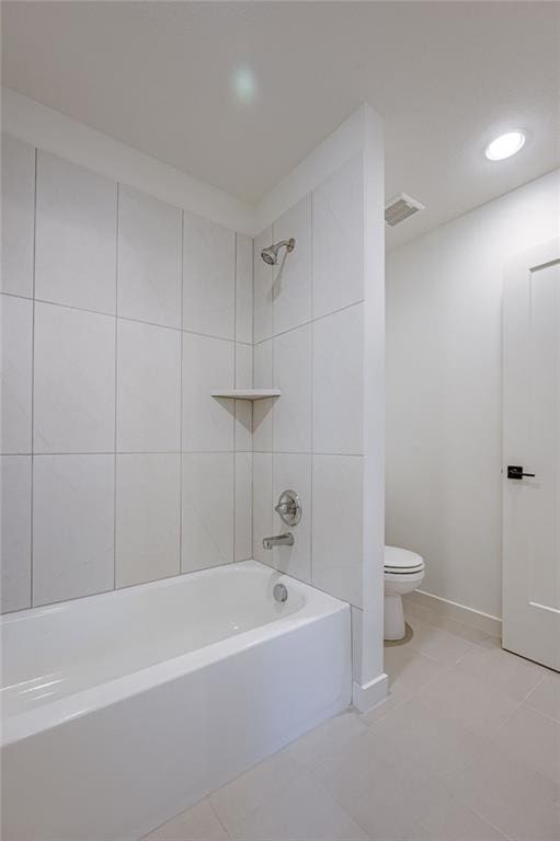 bathroom featuring tiled shower / bath, toilet, and tile floors