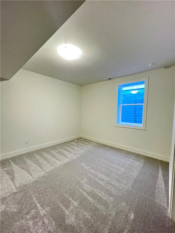 carpeted spare room featuring a textured ceiling