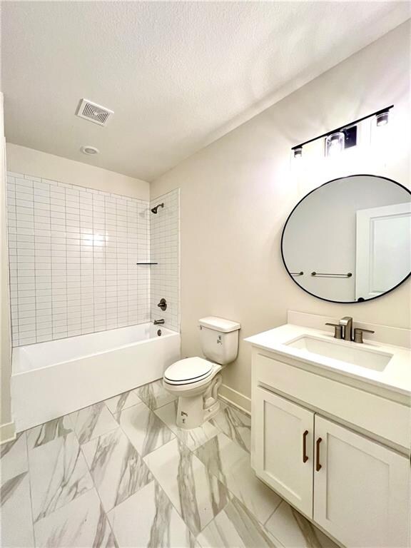 full bathroom featuring toilet, tiled shower / bath, a textured ceiling, and vanity