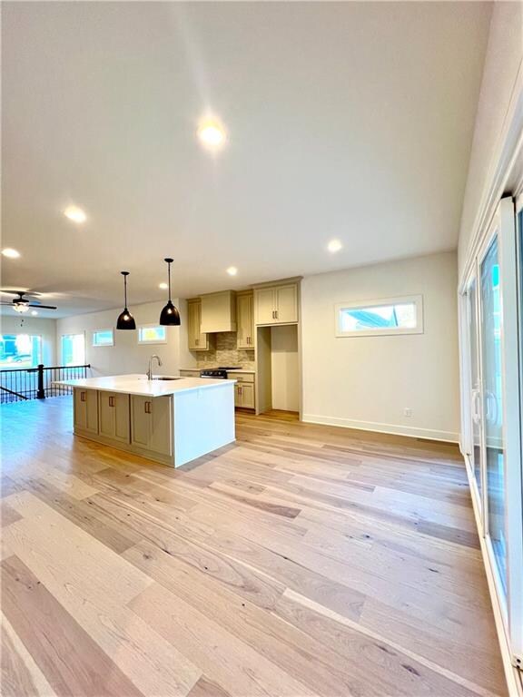 kitchen featuring a center island with sink, light hardwood / wood-style flooring, pendant lighting, and ceiling fan