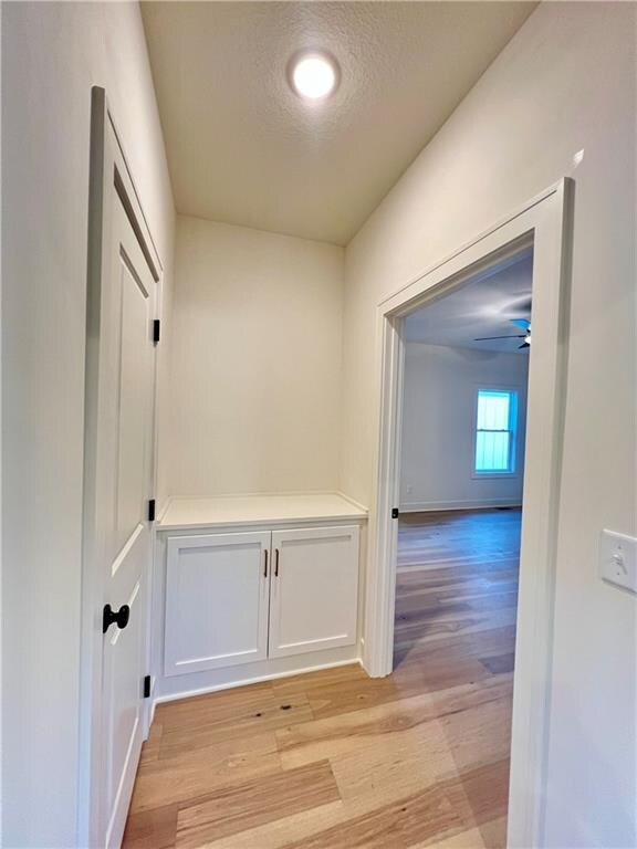 hall featuring light hardwood / wood-style flooring and a textured ceiling