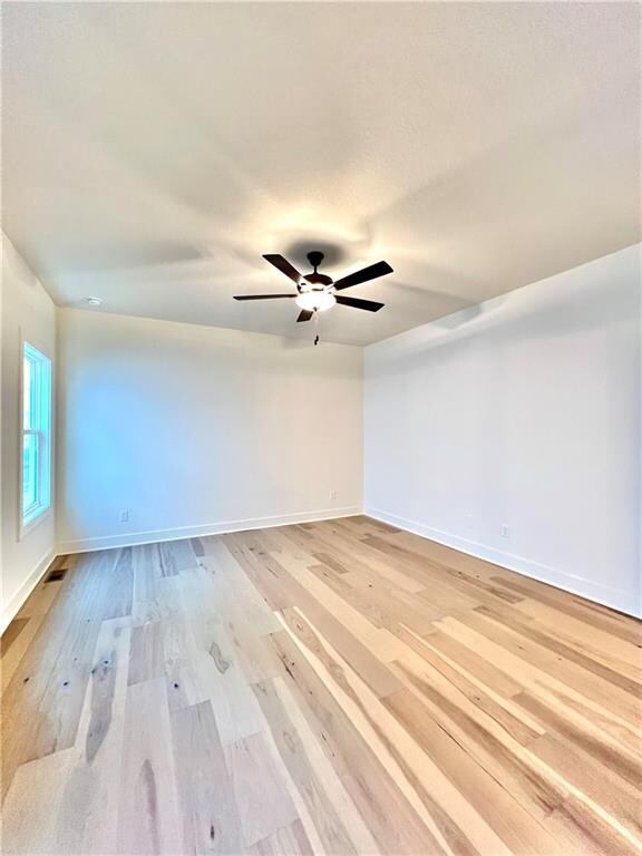 unfurnished room with light wood-type flooring and ceiling fan