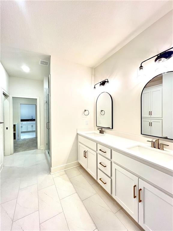 bathroom with vanity, a textured ceiling, and a shower with shower door