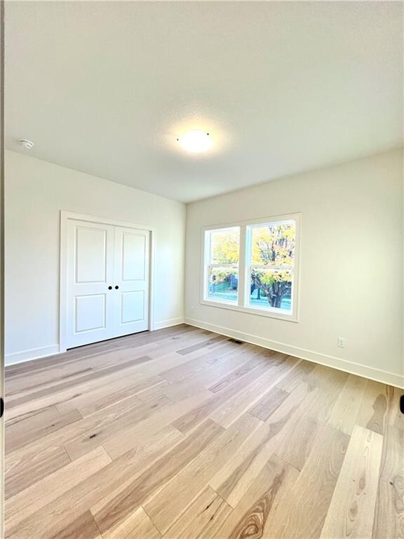 unfurnished bedroom with a closet and light hardwood / wood-style floors