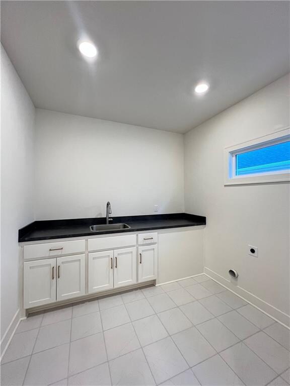 washroom featuring sink, electric dryer hookup, and light tile patterned floors