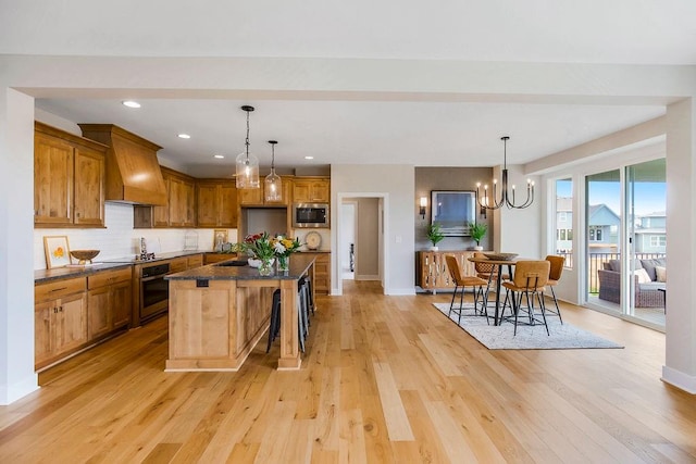 kitchen featuring a breakfast bar, appliances with stainless steel finishes, a center island, light hardwood / wood-style floors, and custom exhaust hood