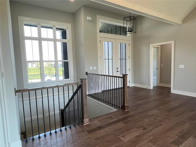 entryway with vaulted ceiling, dark wood-style flooring, a notable chandelier, and baseboards