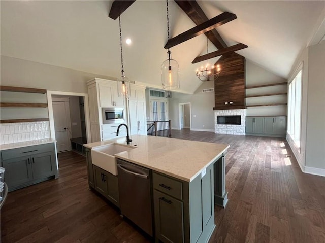 kitchen featuring stainless steel appliances, open floor plan, white cabinetry, a sink, and an island with sink