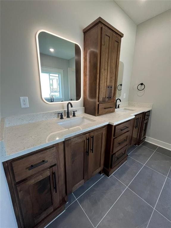 bathroom with tile patterned flooring, a sink, baseboards, and double vanity