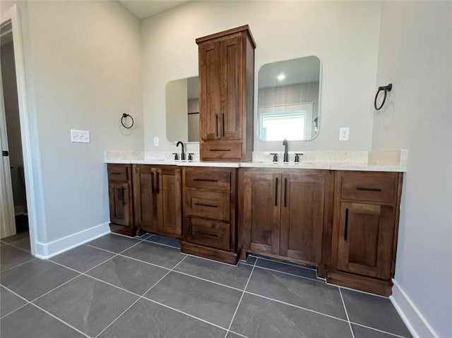 bathroom with a sink, double vanity, tile patterned flooring, and baseboards