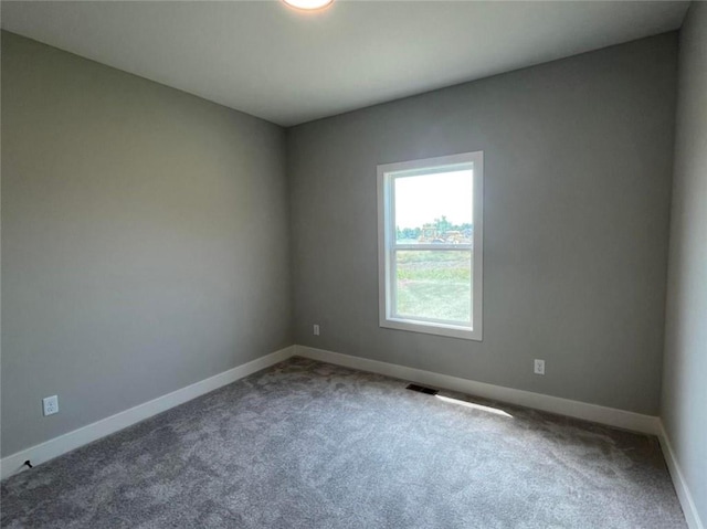 carpeted spare room featuring visible vents and baseboards