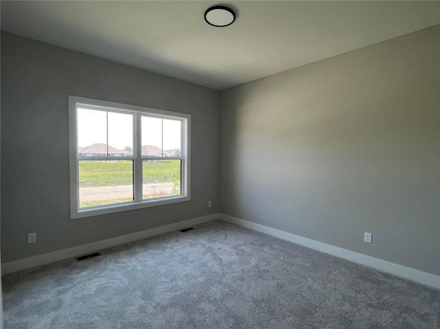 empty room with carpet, visible vents, and baseboards