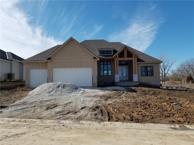 view of front of property featuring board and batten siding, roof with shingles, an attached garage, and central air condition unit