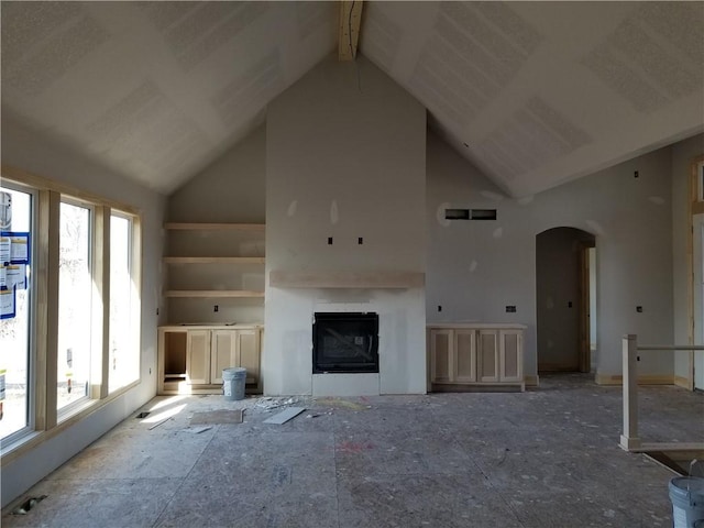 unfurnished living room featuring arched walkways, high vaulted ceiling, and a fireplace