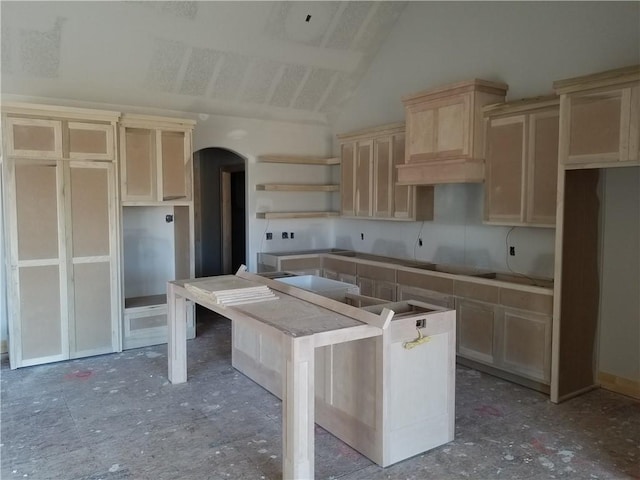 kitchen with open shelves, a kitchen island, arched walkways, and vaulted ceiling