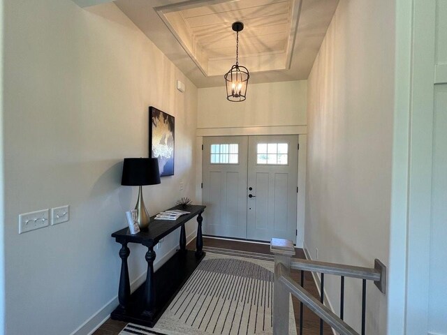 entryway featuring dark hardwood / wood-style flooring, a notable chandelier, and a tray ceiling