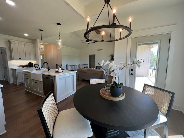 dining area with sink, ceiling fan with notable chandelier, and dark hardwood / wood-style floors