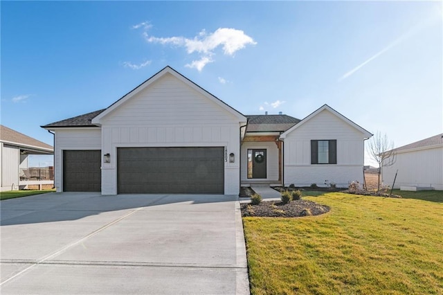 view of front facade with board and batten siding, a front yard, concrete driveway, and an attached garage