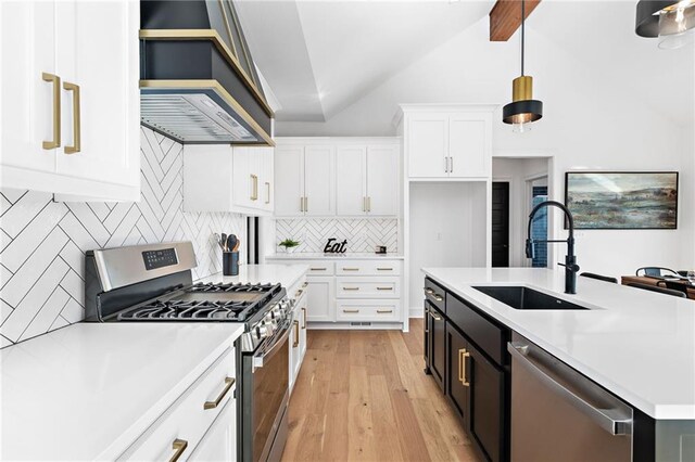 kitchen with sink, premium range hood, hanging light fixtures, vaulted ceiling with beams, and stainless steel appliances