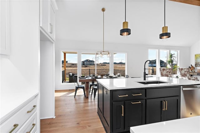 kitchen with decorative light fixtures, sink, white cabinets, stainless steel dishwasher, and light hardwood / wood-style floors