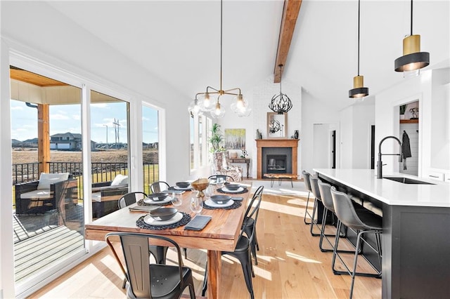 dining area featuring lofted ceiling with beams, sink, and light hardwood / wood-style flooring