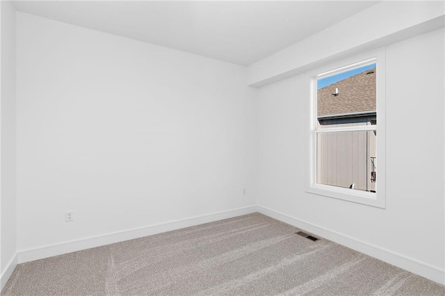 empty room with baseboards, visible vents, and carpet flooring