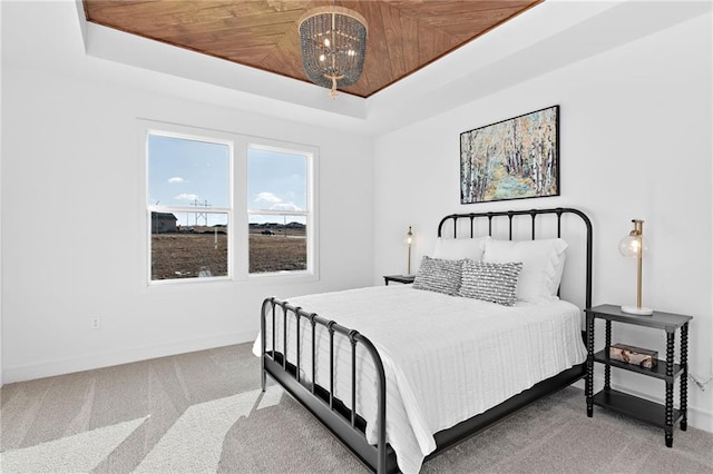 bedroom featuring wood ceiling, carpet flooring, a raised ceiling, and a notable chandelier