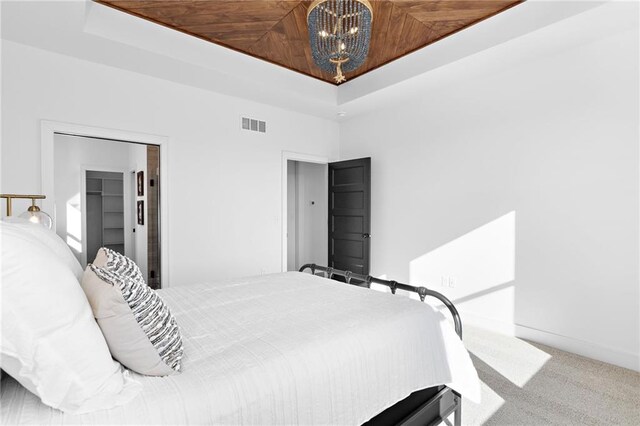 bedroom featuring a tray ceiling, a notable chandelier, wood ceiling, and carpet flooring