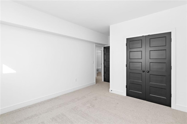 unfurnished bedroom with light carpet and a closet